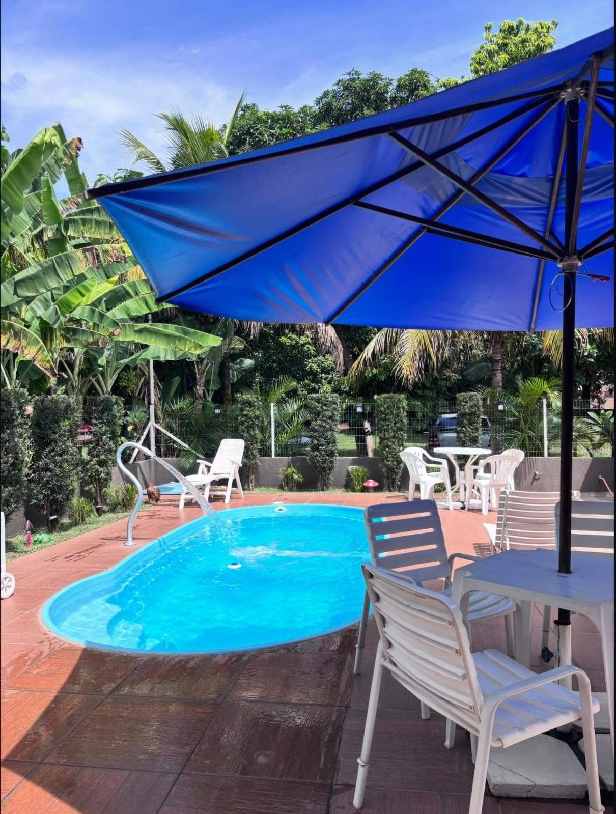 Piscina do Recanto Dokmos com guarda-sol e vegetação ao redor