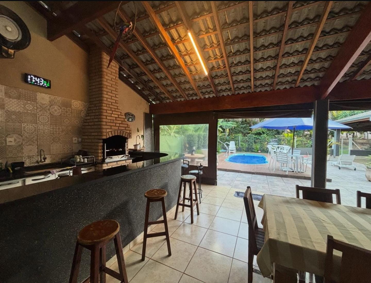 Área gourmet com churrasqueira de tijolinho e vista para a piscina